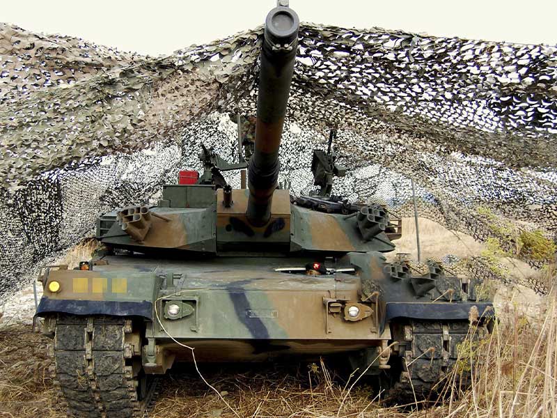 Military tank covered with camouflage net for field protection