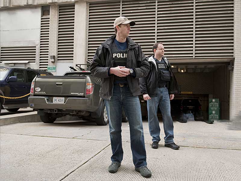 Plainclothes police officers wearing tactical vests outside a building.