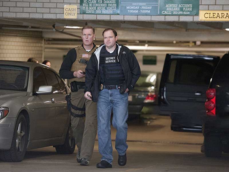 Secret Service officers wearing protective tactical vests in a parking area.