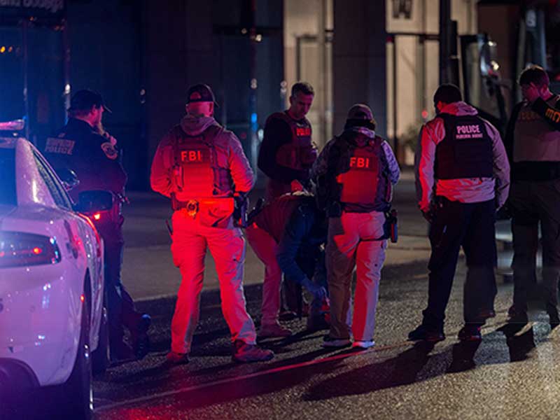 FBI and police officers handling a nighttime law enforcement operation.