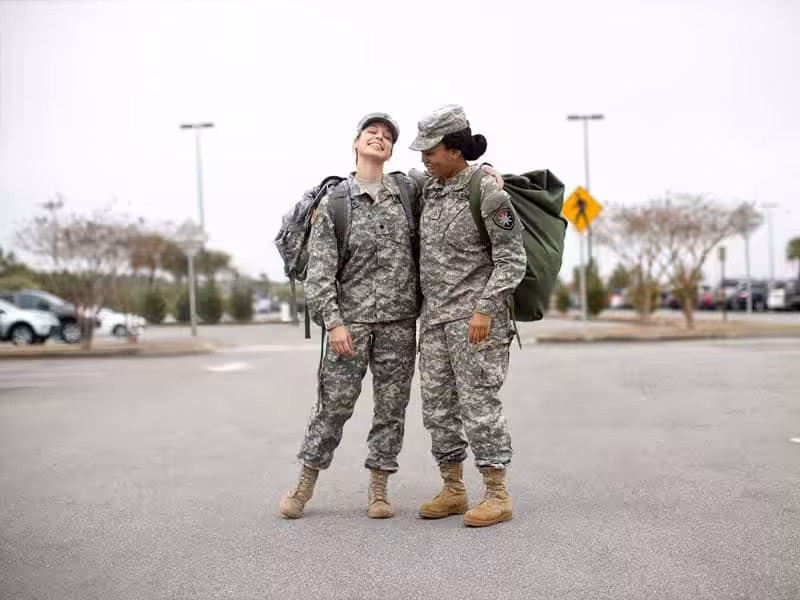 Two female soldiers carrying backpacks.