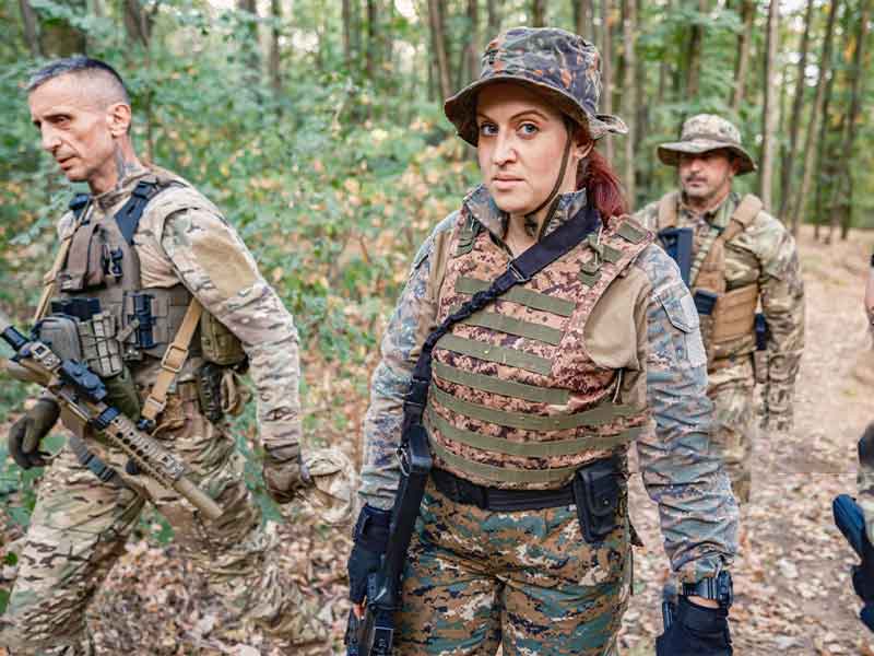 Tactical group wearing camouflage uniforms and protective vests during forest patrol