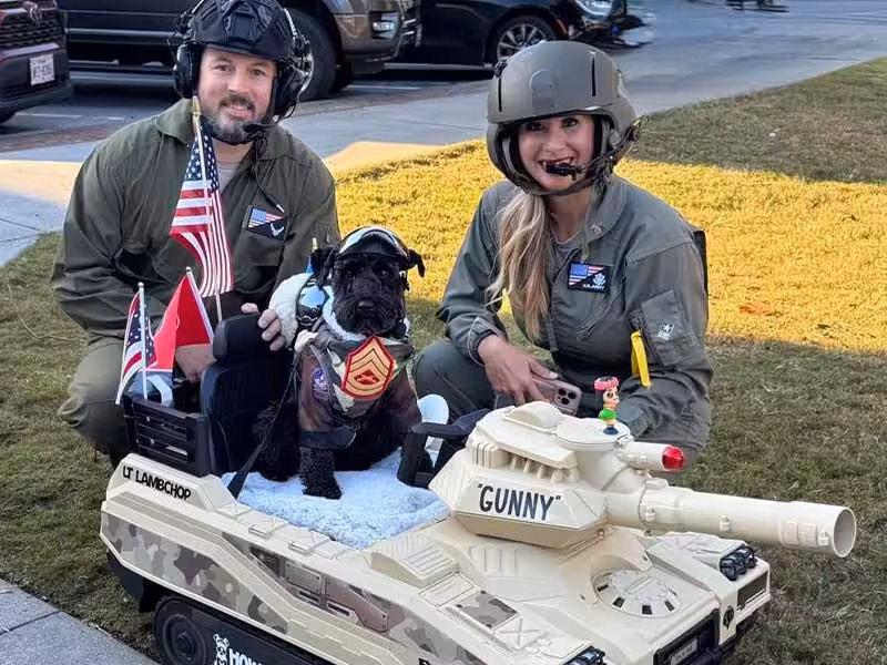 Two people wearing helmets and a dog.